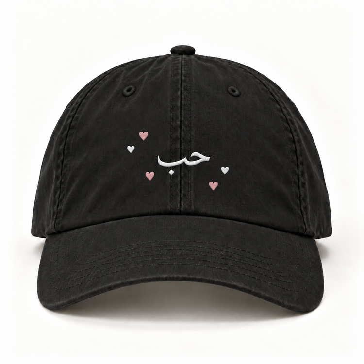 Front view of black Hubb Love cap with white Arabic embroidery and pink and white hearts